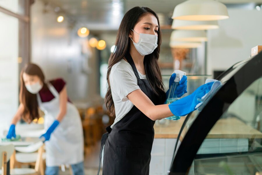 attractive-positive-young-asian-woman-staff-uniform-apron-spraying-detergent-alcohol-counter-product-cabinet-wiping-it-with-soft-cloth-when-disinfecting-cafe-ther-morning-safe-clean_609648-226